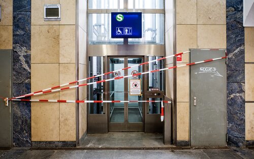 Ein Aufzug ist mit einem rot-weißem Absperrband abgesperrt. Über dem Aufzug befindet sich ein blaues Schild mit dem Symbol für einen Aufzug und einem S-Bahn Symbol.  | © Andi Weiland | Gesellschaftsbilder.de